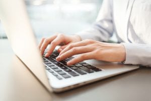 Manos femeninas tecleando en un portátil en la oficina